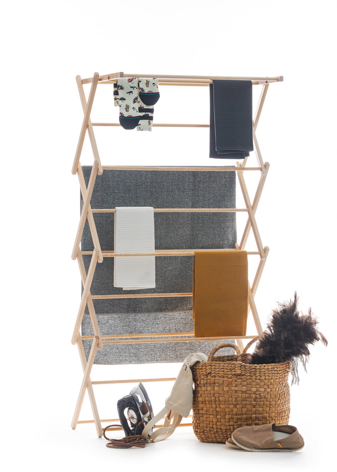 Wooden drying rack with folded clothes on a white background