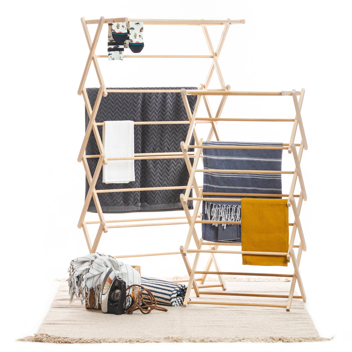Wooden drying rack with folded clothes on a white background